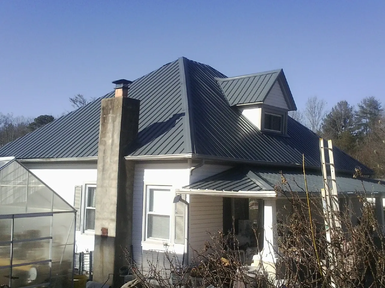 Dark blue standing seam metal roof on a white farmhouse with dormer — Slate & Tile Roof Repair by Roofing Brothers in Farragut
