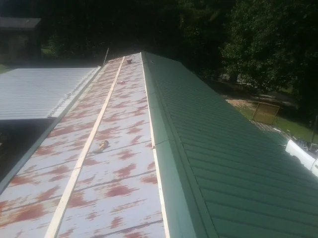 Old rusted panels beside newly installed green metal roofing — Wind Damage Roof Repair by Roofing Brothers in Farragut