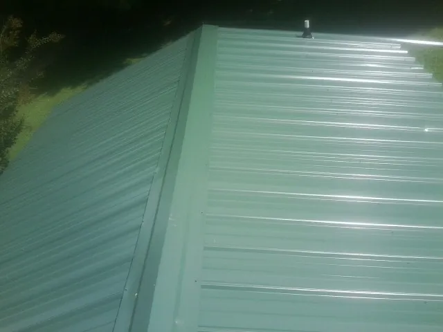 New green metal panels meeting at the ridge of a roof — Flat Roof Repair work by our crew in Farragut