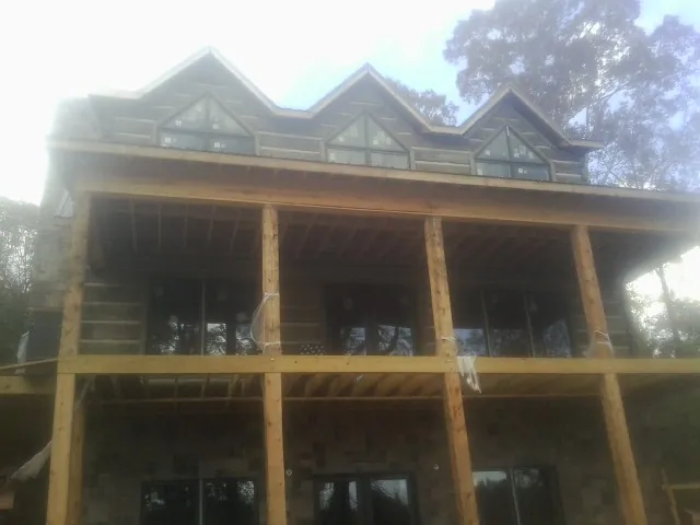 Dormers and porch framing on a large log home under construction — Roof Coating work by our crew in Farragut