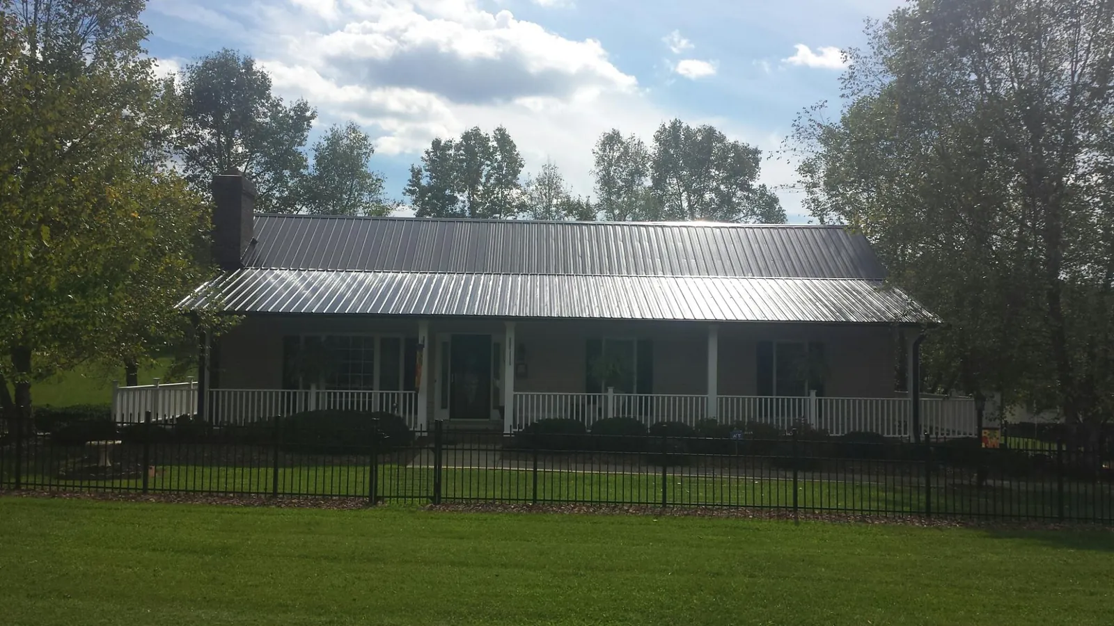 Gray metal roof on a brick ranch with a full width front porch — Gutter Guard Installation work by our crew in Farragut