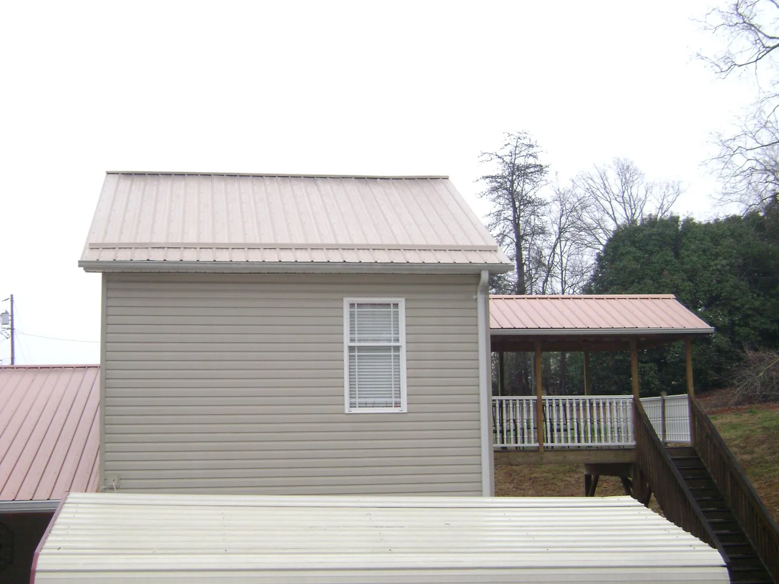 Tan metal roofs on a two story addition and attached porch, from a Roof Replacement job in Farragut