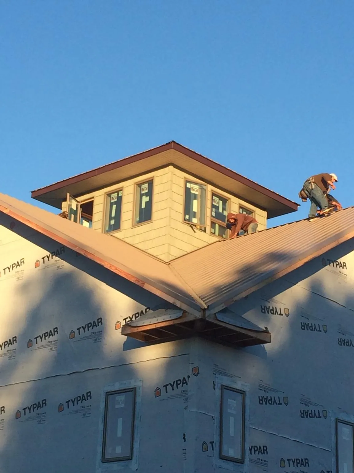 Roofers working around a rooftop cupola on a new metal roof at sunset — Roof Waterproofing in Farragut by Roofing Brothers